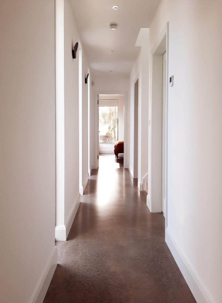 Ispirazione per un ingresso o corridoio minimalista di medie dimensioni con pareti bianche, pavimento in cemento, pavimento grigio, soffitto a volta e pannellatura