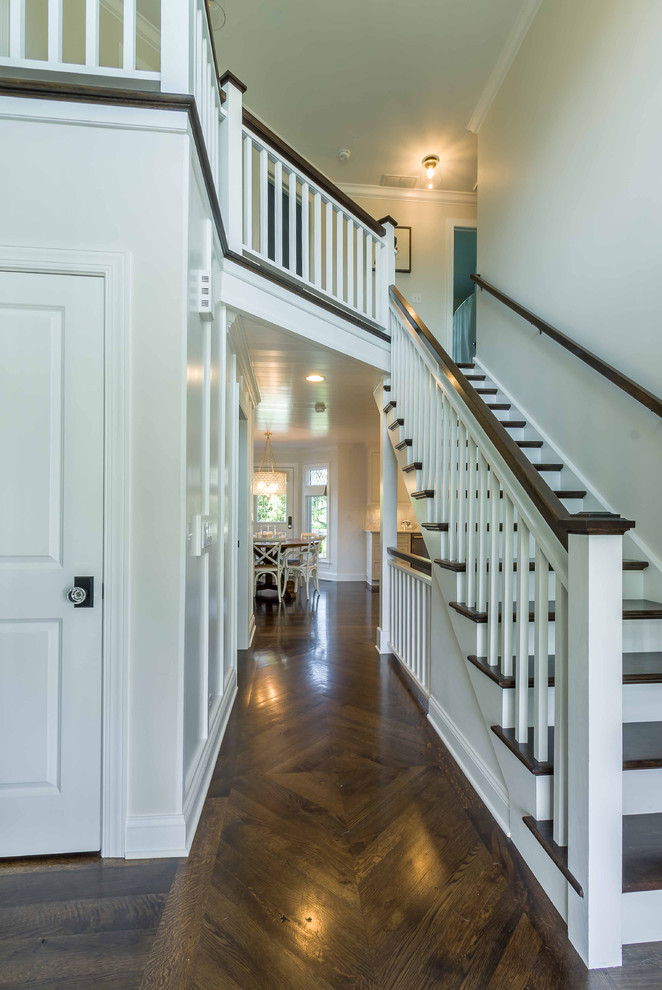 This is an example of a mid-sized traditional wood straight staircase in Chicago with painted wood risers, wood railing and wallpaper.