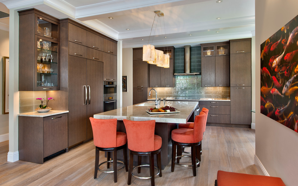 This is an example of a transitional l-shaped kitchen in New York with an undermount sink, flat-panel cabinets, dark wood cabinets, glass tile splashback, stainless steel appliances, light hardwood floors and with island.