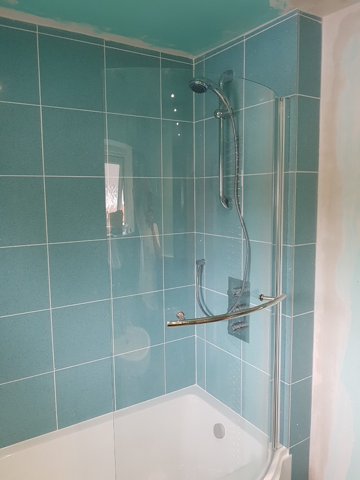 This is an example of a mid-sized traditional kids bathroom in London with a corner tub, an open shower, blue tile, ceramic tile and white walls.