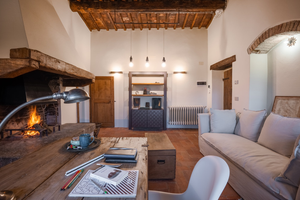 Design ideas for a traditional home studio in Florence with white walls, terracotta flooring, a standard fireplace, a wooden fireplace surround, a freestanding desk, red floors and exposed beams.