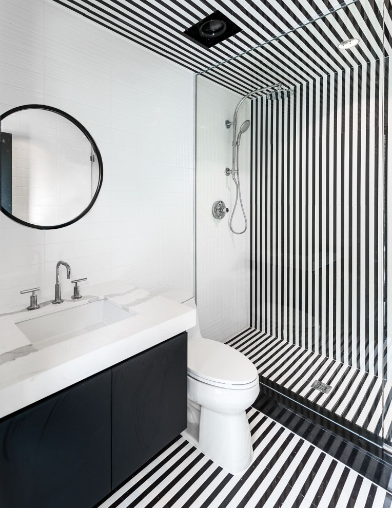 This is an example of a contemporary 3/4 bathroom in Toronto with flat-panel cabinets, black cabinets, an alcove shower, a one-piece toilet, black and white tile, subway tile, an undermount sink, multi-coloured floor, a hinged shower door and white benchtops.