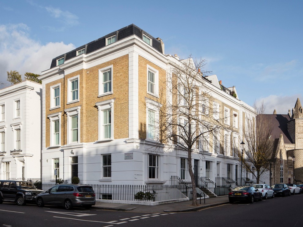 Photo of a large and white modern brick terraced house in London with three floors, a mansard roof and a tiled roof.