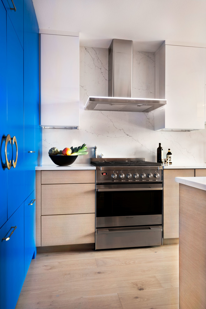 Inspiration for a mid-sized modern eat-in kitchen in Portland with an integrated sink, flat-panel cabinets, blue cabinets, marble benchtops, white splashback, marble splashback, coloured appliances, medium hardwood floors, with island and white benchtop.