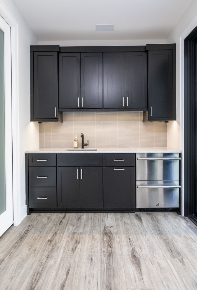 This is an example of a modern single-wall wet bar in Baltimore with an undermount sink, shaker cabinets, dark wood cabinets, beige splashback, matchstick tile splashback, light hardwood floors, multi-coloured floor and white benchtop.