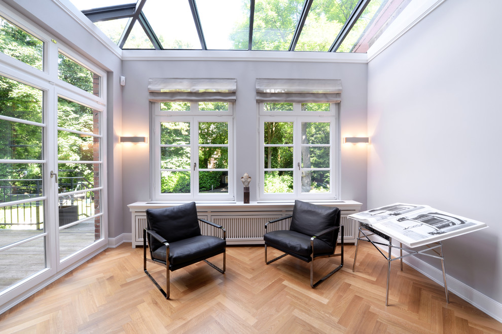 Mid-sized transitional sunroom in Hamburg with light hardwood floors and a glass ceiling.