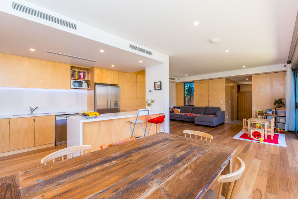 Inspiration for a mid-sized contemporary galley kitchen in Perth with light wood cabinets, quartz benchtops, white splashback, ceramic splashback, stainless steel appliances, medium hardwood floors, with island and white benchtop.