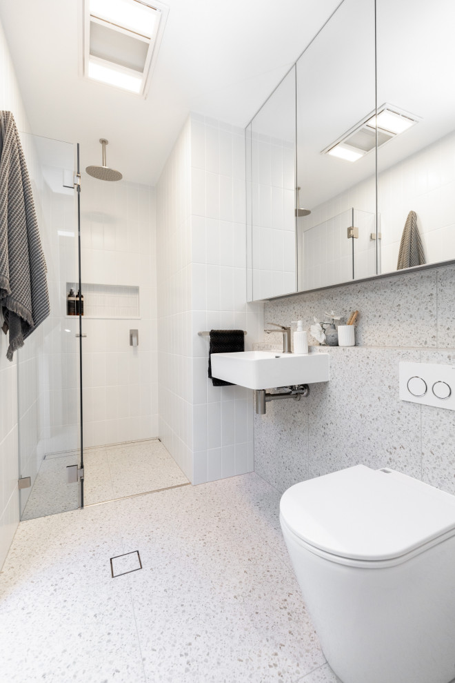 Exempel på ett litet modernt badrum med dusch, med en hörndusch, vit kakel, keramikplattor, klinkergolv i porslin, ett väggmonterat handfat, flerfärgat golv och dusch med gångjärnsdörr