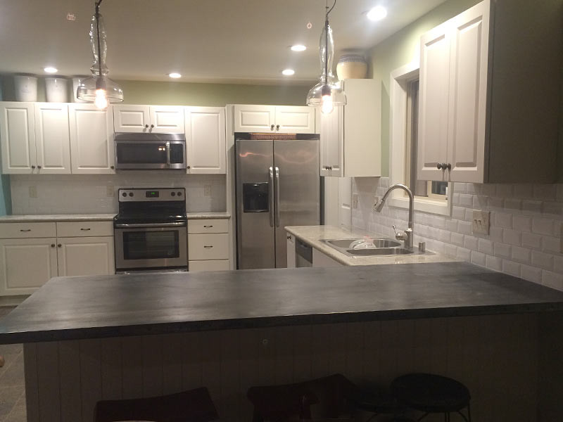Eat-in kitchen - eat-in kitchen idea with a double-bowl sink, recessed-panel cabinets, white cabinets, granite countertops, white backsplash, subway tile backsplash, stainless steel appliances and a peninsula