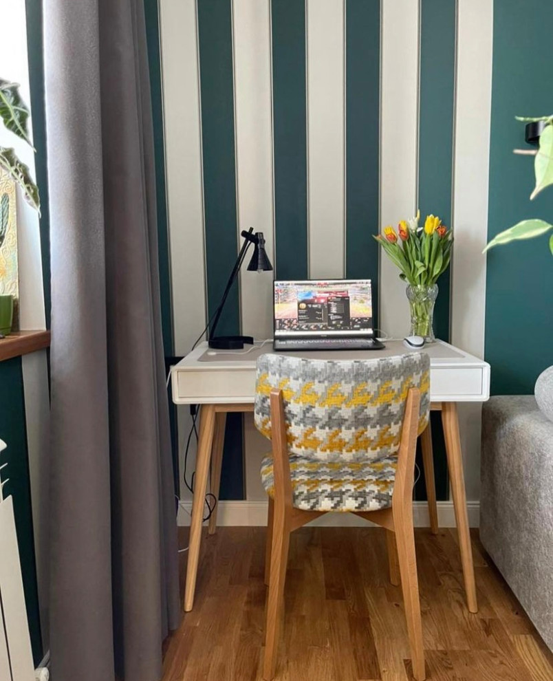 Kleines Nordisches Arbeitszimmer mit Arbeitsplatz, grüner Wandfarbe, braunem Holzboden und freistehendem Schreibtisch in Sonstige