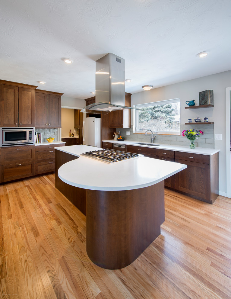 This is an example of a contemporary l-shaped eat-in kitchen in Denver with an undermount sink, shaker cabinets, dark wood cabinets, quartz benchtops, medium hardwood floors and with island.