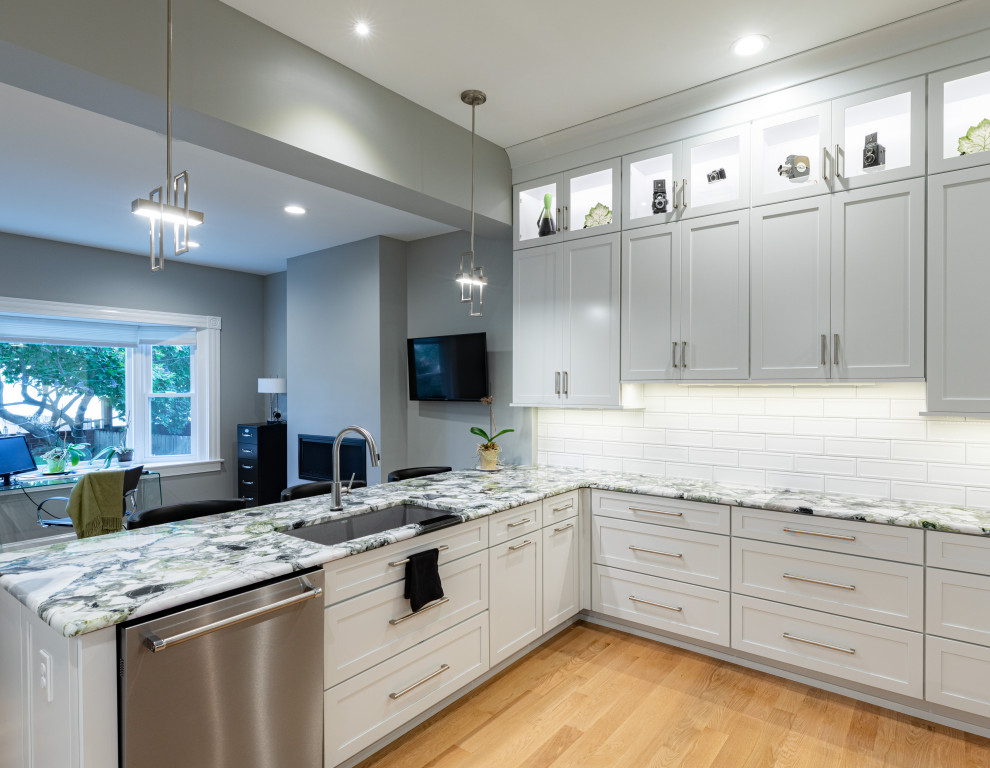 This is an example of a mid-sized transitional u-shaped kitchen in Richmond with an undermount sink, shaker cabinets, white cabinets, quartzite benchtops, white splashback, subway tile splashback, stainless steel appliances and medium hardwood floors.
