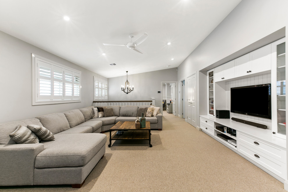 This is an example of a large transitional open concept family room in Melbourne with white walls, carpet, no fireplace, a wall-mounted tv and beige floor.