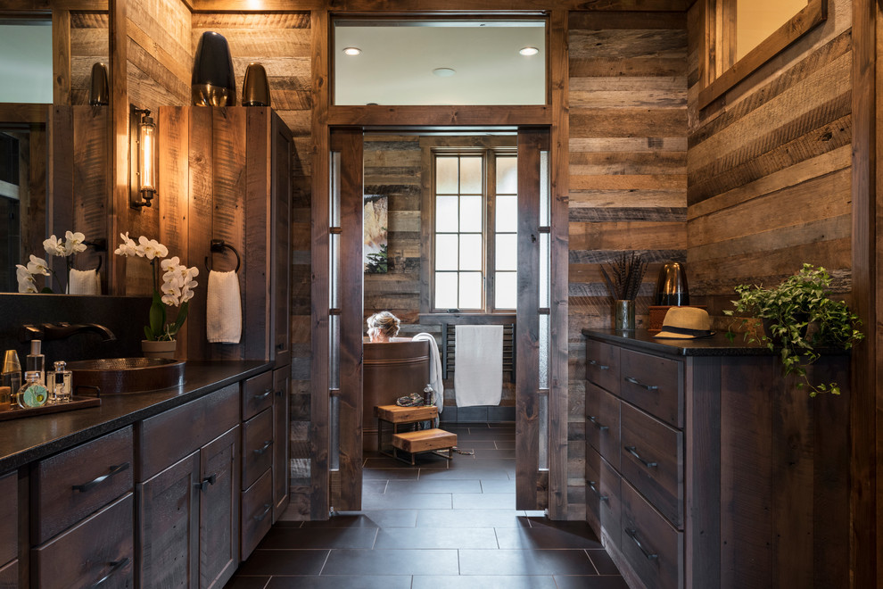 Large country master bathroom in Other with flat-panel cabinets, dark wood cabinets, a japanese tub, a curbless shower, a one-piece toilet, brown walls, porcelain floors, a hinged shower door, a drop-in sink and black floor.