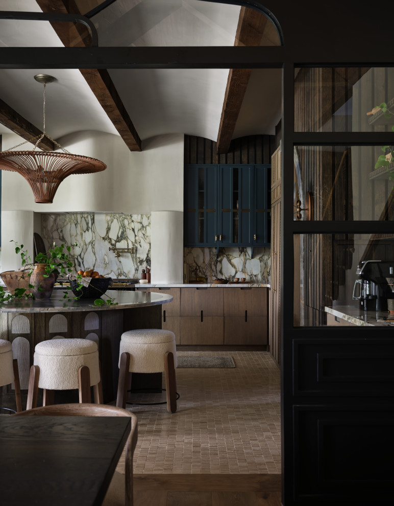 Barrel & Beam - The kitchen at Southlake Manor underwent a full transformation, drawing inspiration from the charm of the South of France while incorporating the Denningtons' personal tastes. A major design feature is the stunning barrelled ceiling, which adds a sense of grandeur and architectural interest. This beautiful ceiling design enhances the space by creating visual height, drawing the eye upward and contributing to the kitchen’s airy and open feel.
The Denningtons’ love for the color blue is woven throughout the kitchen, with custom accents in a rich, deep shade that adds warmth and personality to the space. The cabinetry features a mix of finishes that complement the color palette, creating a balanced, sophisticated look.
At the heart of the kitchen sits a custom, round island—a standout piece designed to be both functional and visually striking. The island, with its unique shape and built-in drawers, provides ample storage while maintaining a sleek, clean aesthetic. It’s an ideal gathering spot for the family and offers a beautiful contrast to the surrounding cabinetry.
The layers of texture throughout the kitchen—from the smooth cabinetry finishes to the intricate details of the island and the natural warmth of the new barrelled ceiling—add depth and dimension. Every element is carefully crafted to elevate the design to the next level, blending style with practicality in a way that reflects the Denningtons' love for sophisticated, yet welcoming spaces.