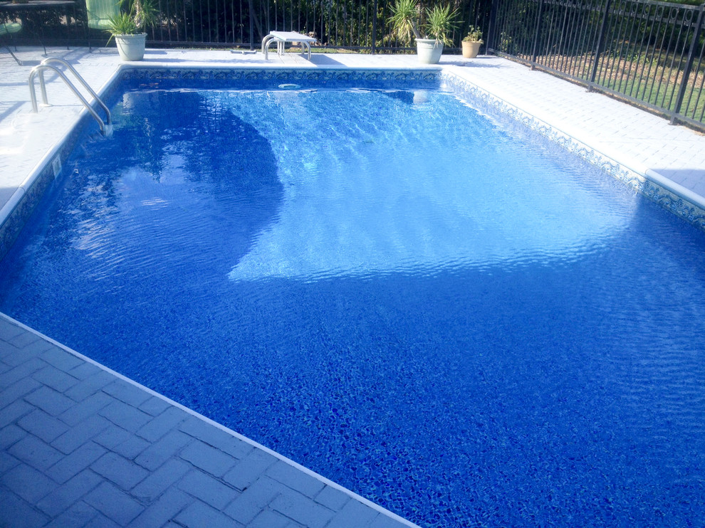 Example of a transitional backyard brick and custom-shaped natural pool design