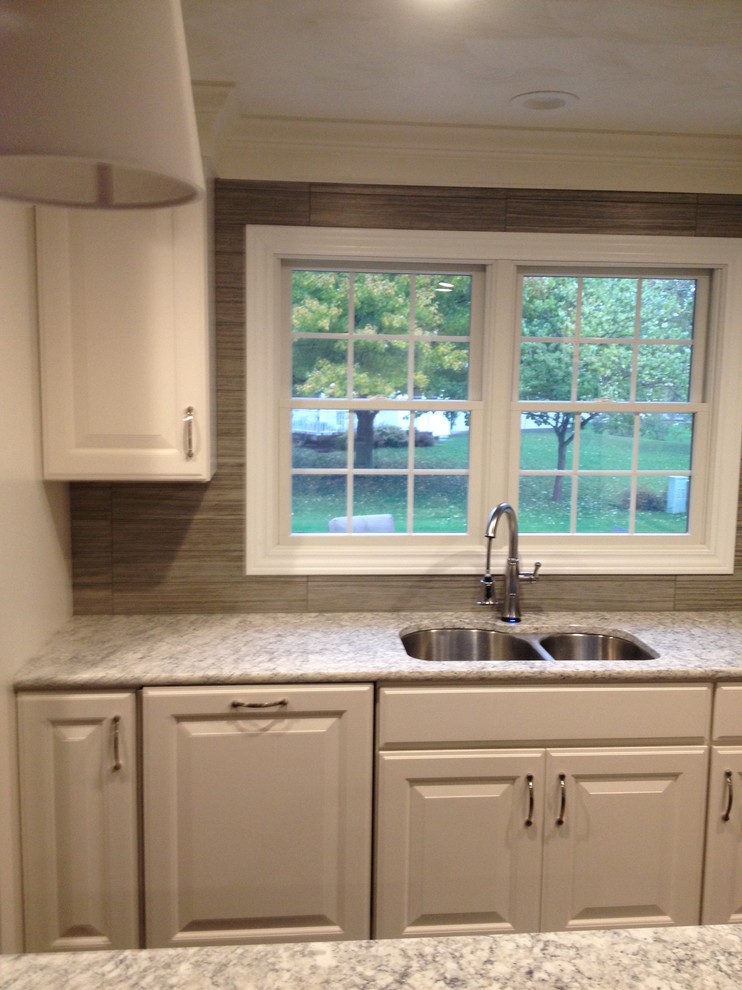 Example of a mid-sized transitional single-wall dark wood floor eat-in kitchen design in Chicago with raised-panel cabinets, white cabinets, granite countertops, gray backsplash, ceramic backsplash, stainless steel appliances and an island