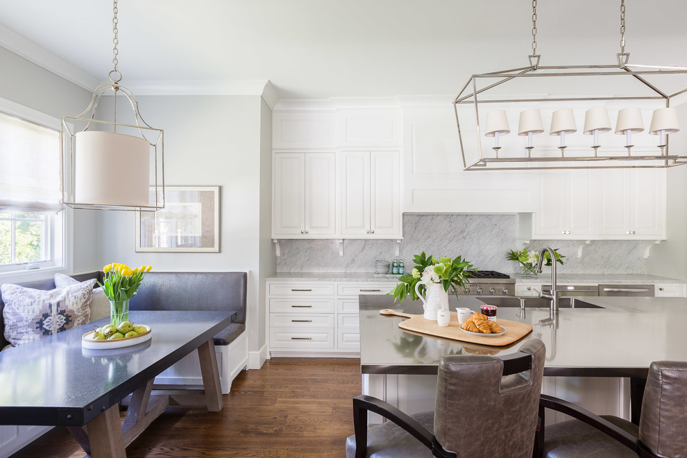 Inspiration for a mid-sized transitional medium tone wood floor eat-in kitchen remodel with a farmhouse sink, white cabinets, gray backsplash, marble backsplash, stainless steel appliances and an island