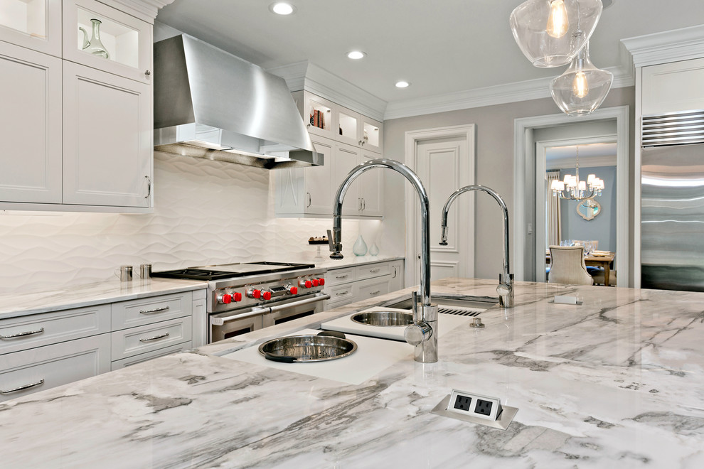 Inspiration for a large transitional l-shaped open plan kitchen in Dallas with an undermount sink, glass-front cabinets, white cabinets, granite benchtops, white splashback, porcelain splashback, stainless steel appliances, medium hardwood floors, with island and brown floor.