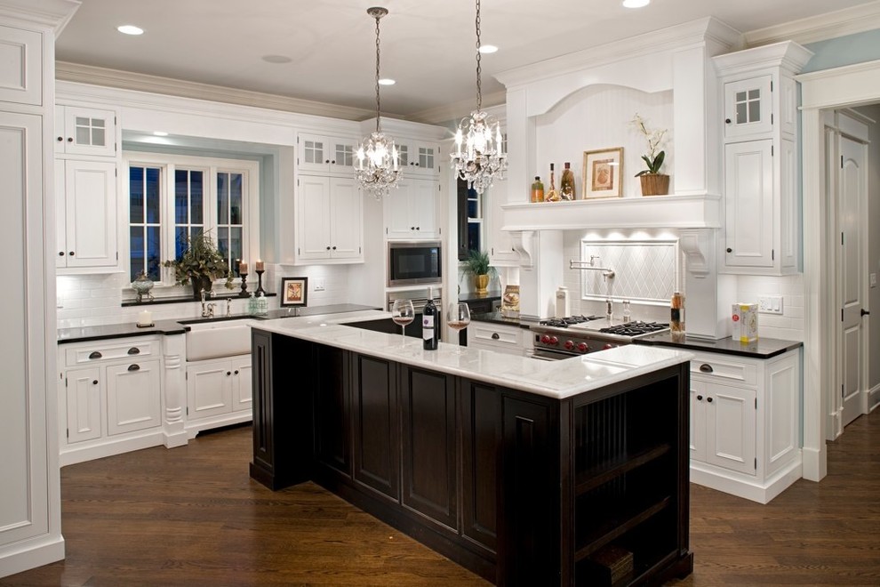 Design ideas for a mid-sized traditional l-shaped separate kitchen in Chicago with marble benchtops, stainless steel appliances, a farmhouse sink, recessed-panel cabinets, white splashback, subway tile splashback, medium hardwood floors and with island.