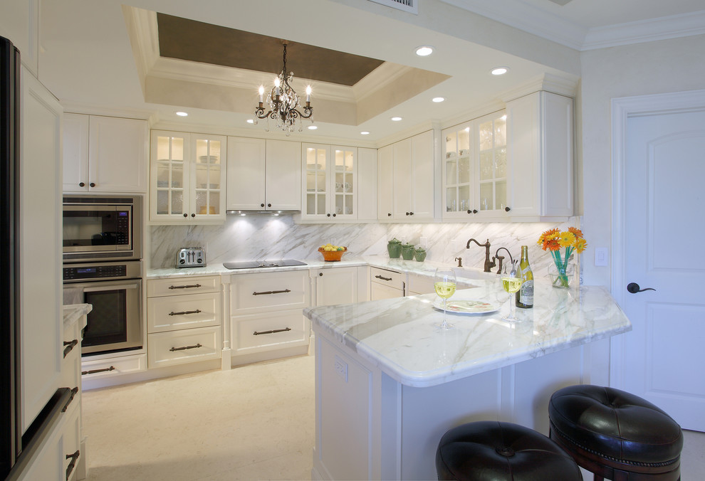 Inspiration for a large traditional u-shaped open plan kitchen in Miami with an undermount sink, recessed-panel cabinets, white cabinets, marble benchtops, multi-coloured splashback, limestone splashback, stainless steel appliances, porcelain floors, no island, white floor and multi-coloured benchtop.