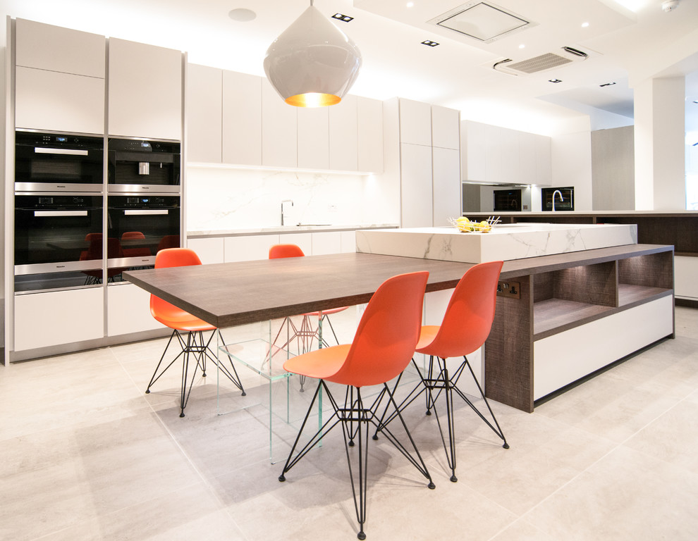 Photo of a medium sized modern single-wall open plan kitchen in London with an integrated sink, flat-panel cabinets, white cabinets, marble worktops, white splashback, marble splashback, stainless steel appliances and no island.