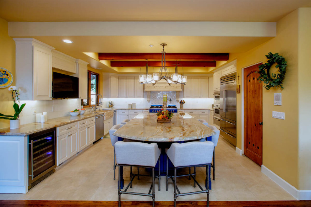 Large eclectic u-shaped porcelain tile, beige floor and exposed beam enclosed kitchen photo in San Francisco with a farmhouse sink, raised-panel cabinets, blue cabinets, granite countertops, beige backsplash, marble backsplash, colored appliances, an island and multicolored countertops