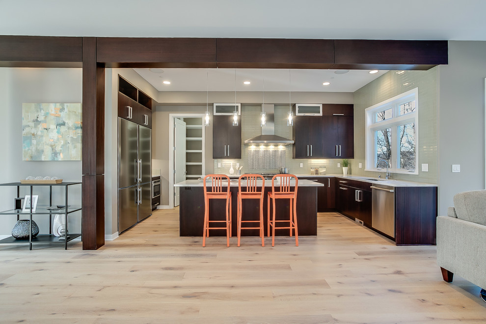 Inspiration for a mid-sized contemporary u-shaped eat-in kitchen in Seattle with an undermount sink, flat-panel cabinets, brown cabinets, solid surface benchtops, green splashback, glass tile splashback, stainless steel appliances, light hardwood floors, with island and beige floor.