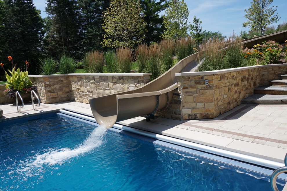 Photo of a large transitional backyard rectangular lap pool in Other with a water slide and concrete pavers.