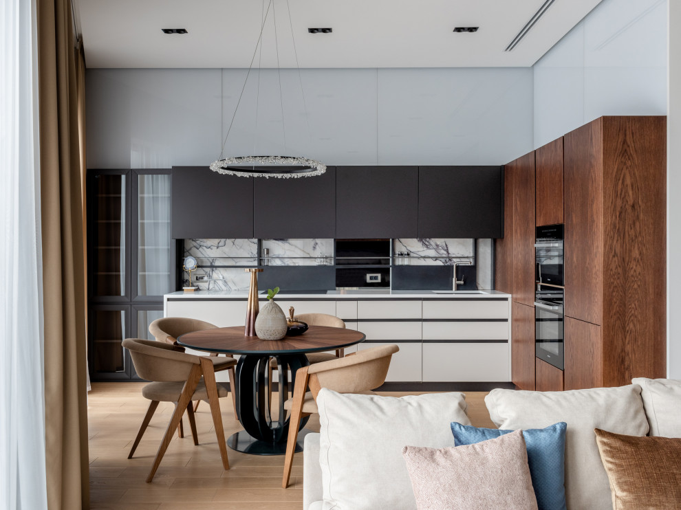 Design ideas for a contemporary l-shaped open plan kitchen in Moscow with an undermount sink, flat-panel cabinets, dark wood cabinets, black appliances, light hardwood floors, no island, beige floor and white benchtop.