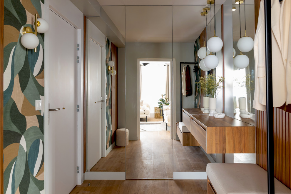 Mittelgroßes Modernes Foyer mit hellem Holzboden, braunem Boden, grauer Wandfarbe, weißer Haustür und vertäfelten Wänden in Paris