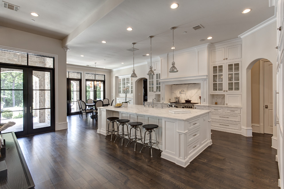 Photo of a traditional open plan kitchen in Dallas with recessed-panel cabinets, white cabinets, white splashback, stone slab splashback and dark hardwood floors.