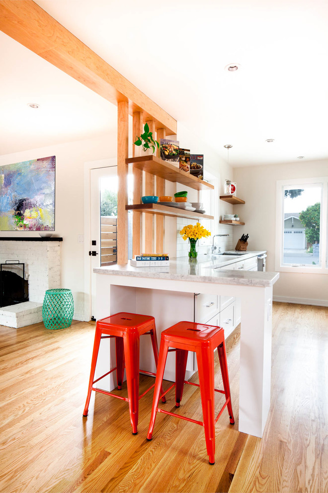 Mid-sized modern galley eat-in kitchen in San Francisco with shaker cabinets, a peninsula, an undermount sink, white cabinets, marble benchtops, white splashback, ceramic splashback, stainless steel appliances, light hardwood floors and brown floor.