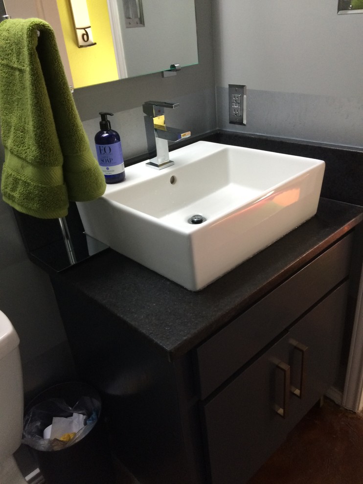 This is an example of a small contemporary bathroom in Austin with shaker cabinets, blue cabinets, a two-piece toilet, blue walls, concrete floors, a vessel sink, red floor and black benchtops.