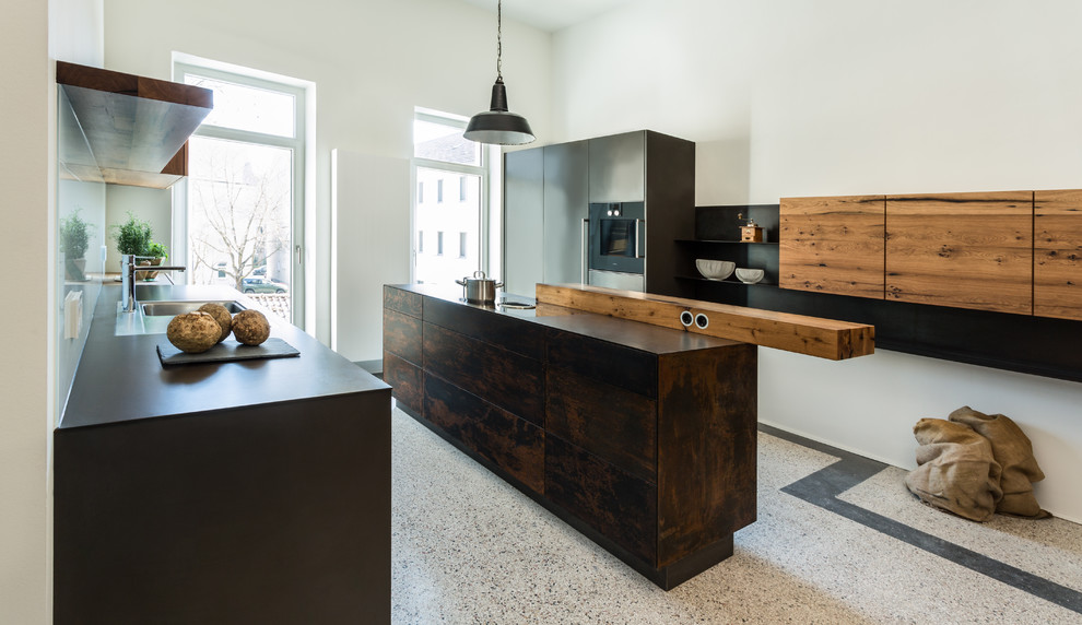 Inspiration for a contemporary galley kitchen in Stuttgart with flat-panel cabinets, glass sheet splashback, black appliances, terrazzo floors, with island and multi-coloured floor.