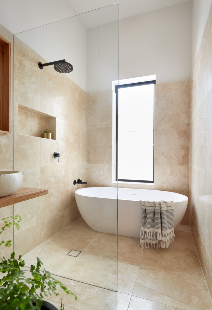 This is an example of a small contemporary 3/4 bathroom in Melbourne with glass-front cabinets, brown cabinets, a freestanding tub, an open shower, beige tile, a vessel sink, wood benchtops, an open shower and brown benchtops.
