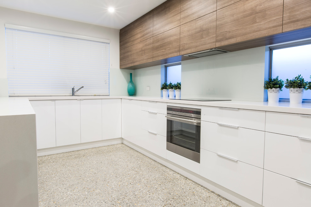 Design ideas for a mid-sized modern u-shaped eat-in kitchen in Perth with an undermount sink, light wood cabinets, quartz benchtops, white splashback, glass sheet splashback, stainless steel appliances, concrete floors and no island.