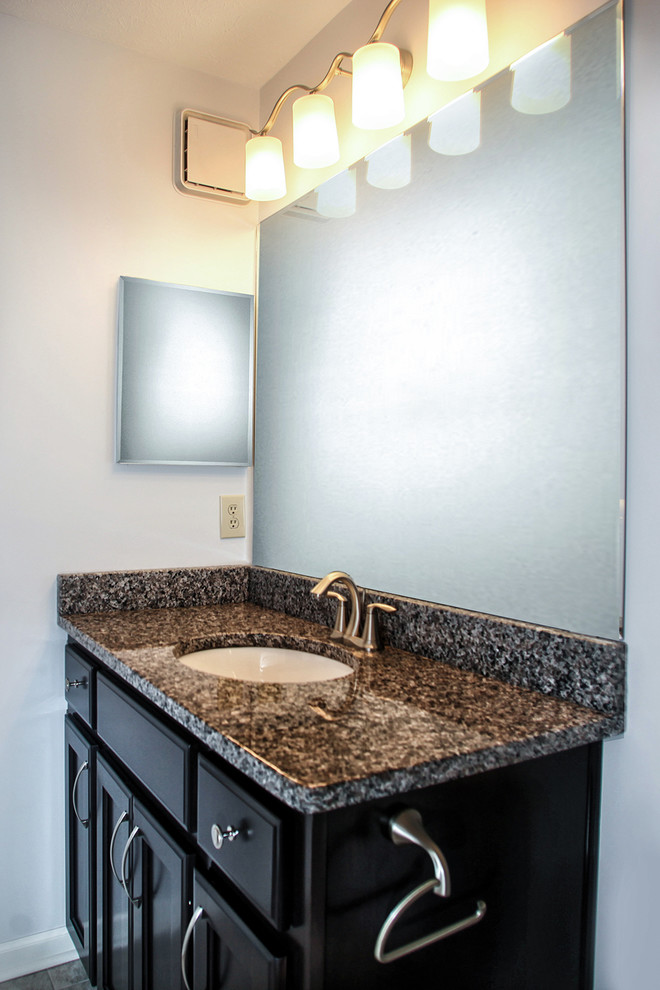 Photo of a mid-sized traditional 3/4 bathroom in Louisville with an undermount sink, furniture-like cabinets, medium wood cabinets, granite benchtops, an alcove shower, a two-piece toilet, multi-coloured tile, ceramic tile, white walls and ceramic floors.