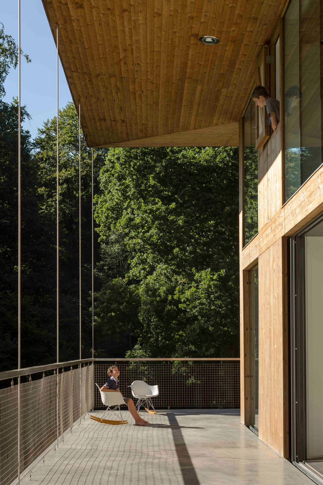 Photo of a large contemporary backyard deck in London with a roof extension.