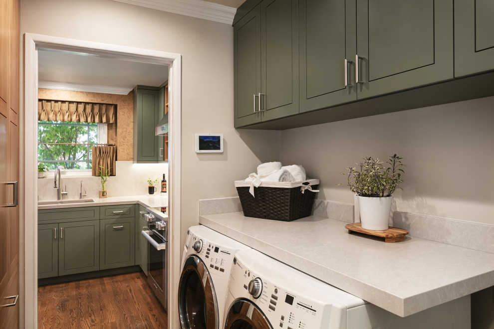 This is an example of a small eclectic galley separated utility room in Los Angeles with raised-panel cabinets, green cabinets, engineered stone countertops, beige walls, dark hardwood flooring, a side by side washer and dryer and white worktops.