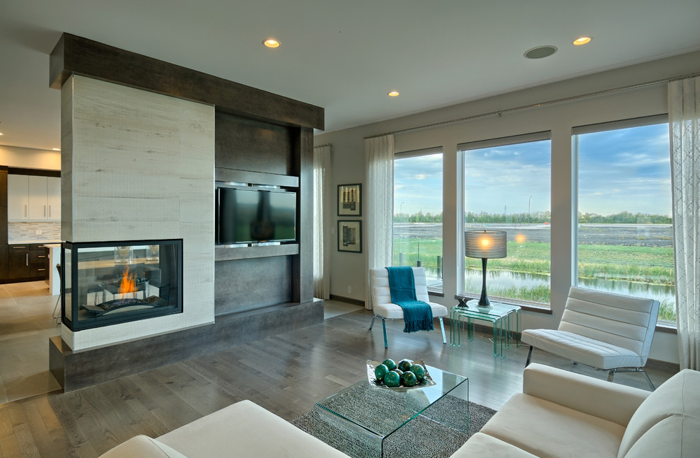 Inspiration for a mid-sized contemporary open concept living room in Other with beige walls, dark hardwood floors, a two-sided fireplace, a wood fireplace surround, a wall-mounted tv and brown floor.