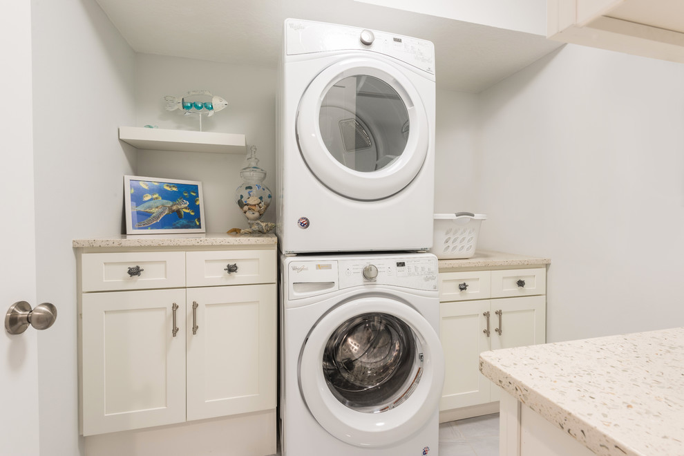 Inspiration for a mid-sized transitional galley dedicated laundry room in Orlando with shaker cabinets, white cabinets, recycled glass benchtops, grey walls, porcelain floors, a stacked washer and dryer, grey floor and multi-coloured benchtop.