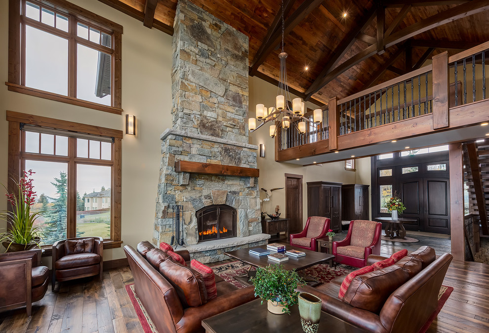 Large country open concept living room in Calgary with a standard fireplace, a stone fireplace surround, beige walls and dark hardwood floors.