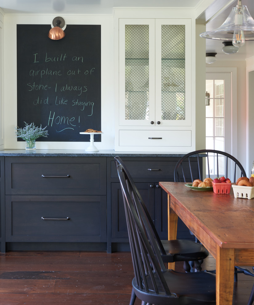 Large country dark wood floor and brown floor kitchen/dining room combo photo in New York with shaker cabinets, black cabinets, soapstone countertops, paneled appliances, an island and white walls
