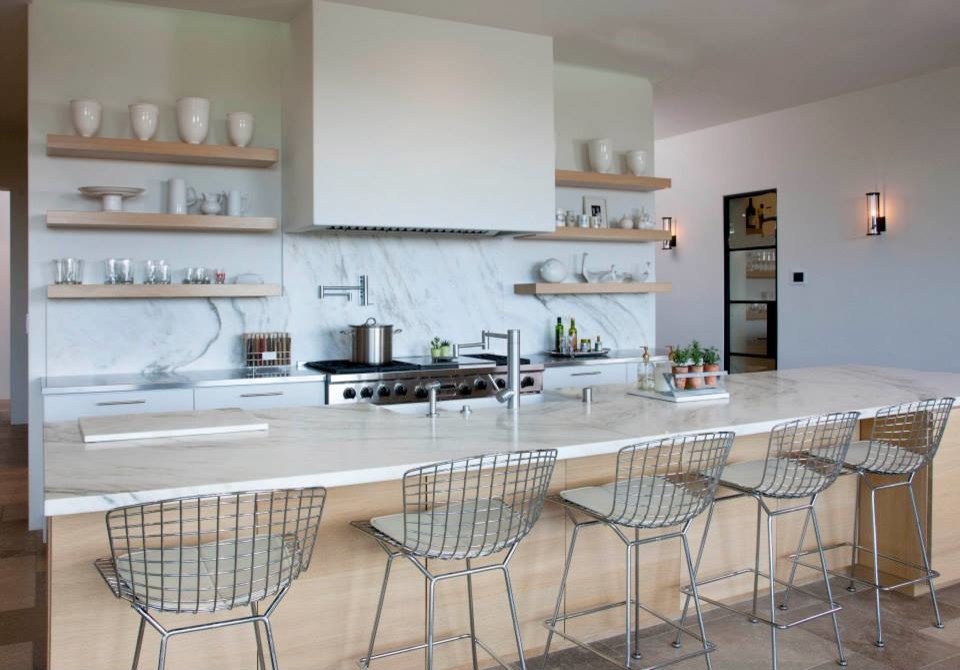 Design ideas for a large contemporary single-wall eat-in kitchen in San Diego with a farmhouse sink, flat-panel cabinets, white cabinets, marble benchtops, white splashback, stone slab splashback, stainless steel appliances, with island, limestone floors and brown floor.