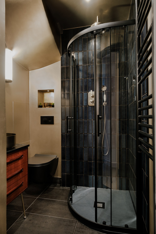 Modelo de cuarto de baño de pie ecléctico pequeño con ducha esquinera, sanitario de pared, suelo de baldosas de porcelana, aseo y ducha, encimera de cuarcita, suelo negro, ducha con puerta corredera y encimeras negras
