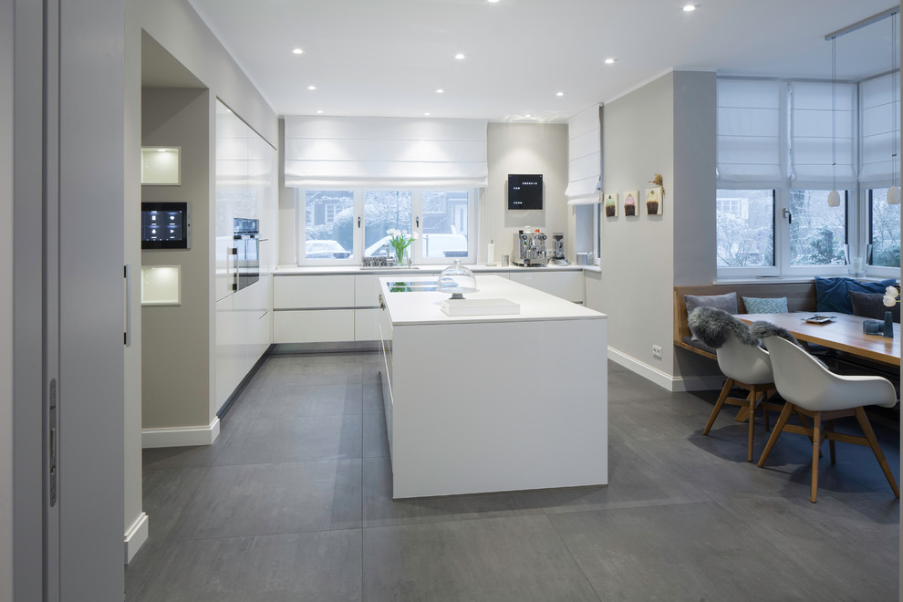 Mid-sized scandinavian l-shaped separate kitchen in Hamburg with an integrated sink, flat-panel cabinets, white cabinets, white splashback, black appliances, with island and grey floor.