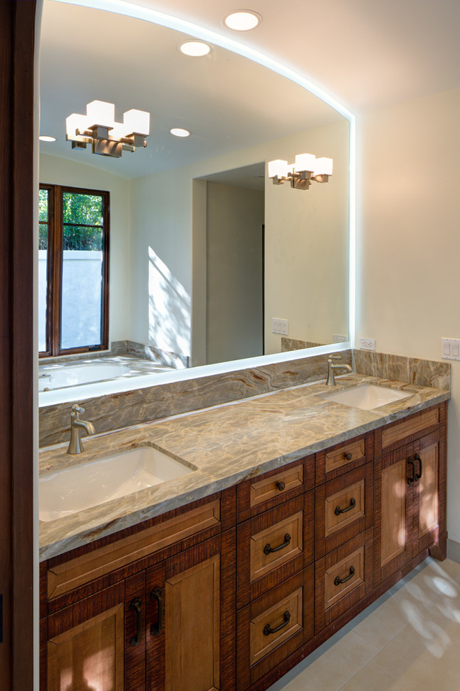 Design ideas for a mid-sized mediterranean master bathroom in San Diego with beige walls, cement tiles, an undermount sink, grey floor, an undermount tub, a corner shower, a hinged shower door, raised-panel cabinets, medium wood cabinets and quartzite benchtops.