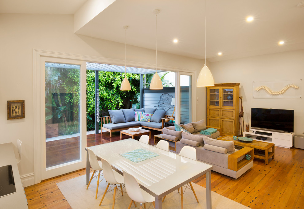 This is an example of a mid-sized beach style dining room in Sydney with white walls and medium hardwood floors.