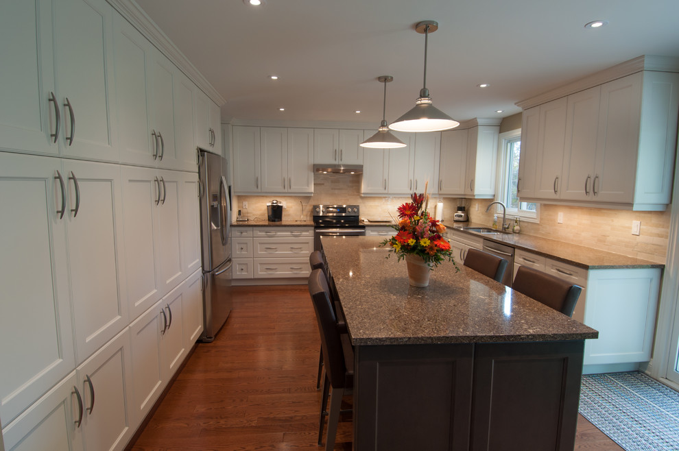 Example of a large transitional u-shaped medium tone wood floor enclosed kitchen design in Toronto with a double-bowl sink, shaker cabinets, white cabinets, granite countertops, beige backsplash, ceramic backsplash, stainless steel appliances and an island